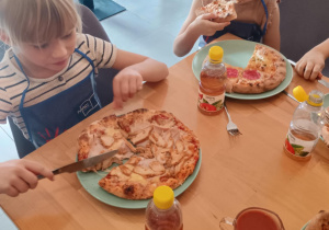 Dzieci konsumują pizzę.
