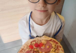 Dziecko z własnoręcznie zrobioną pizzą.