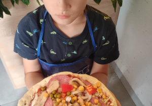 Dziecko z własnoręcznie zrobioną pizzą.