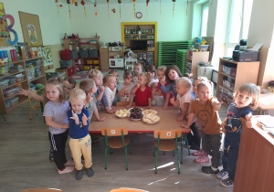 Dzieci przy stoliku obok owoców.
