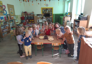 Dzieci przy stoliku obok owoców.