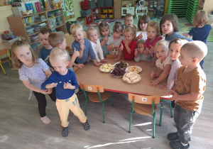 Dzieci przy stoliku obok owoców.