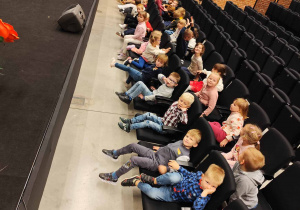 Dzieci siedzą na widowni i oglądają przedstawienie.