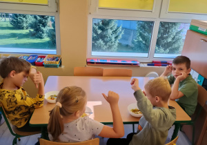 Dzieci przy stolikach kroją owoce na sałatkę.