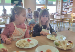 Dzieci przy stolikach robią szaszłyki.