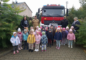 Zdjęcie grupowe ze strażakami przed autem strażackim.