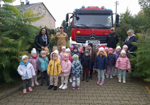 Zdjęcie grupowe ze strażakami przed autem strażackim.