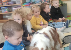 Piesek liże dzieci po paluszku posmarowanym smakołykiem.