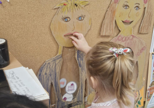 Dziecko wkłada do sylwety produkt spożywczy.