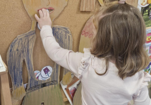 Dziecko wkłada do sylwety produkt spożywczy.