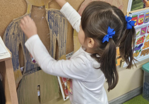 Dziecko wkłada do sylwety produkt spożywczy.