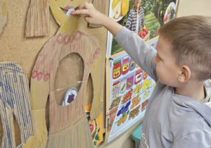 Dziecko wkłada do sylwety produkt spożywczy.