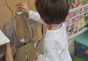 Dziecko wkłada do sylwety produkt spożywczy.