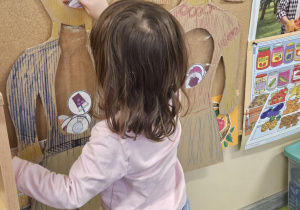 Dziecko wkłada do sylwety produkt spożywczy.