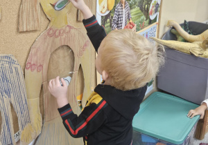 Dziecko wkłada do sylwety produkt spożywczy.