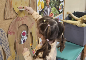 Dziecko wkłada do sylwety produkt spożywczy.