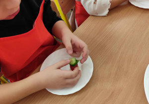 Dzieci przygotowują koreczki z warzyw.