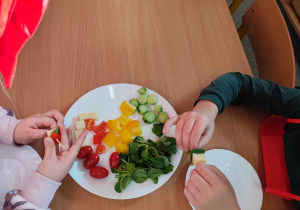 Dzieci przygotowują koreczki z warzyw.