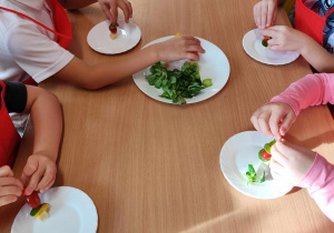 Dzieci przygotowują koreczki z warzyw.