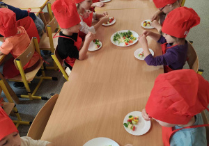 Dzieci przygotowują koreczki z warzyw.