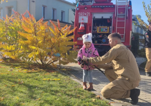 Dziecko leje wodę z węża strażackiego.