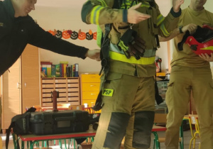 Strażacy pokazują strój.