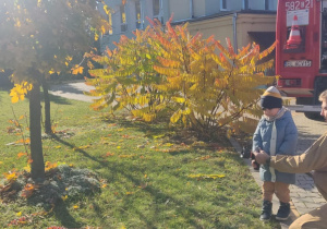 Dziecko leje wodę z węża strażackiego.