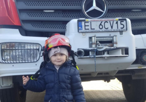 Dziecko w kasku strażackim.