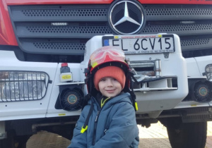 Dziecko w kasku strażackim.