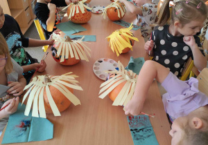 Dzieci tworzą postacie z dyni.