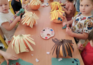 Dzieci tworzą postacie z dyni.