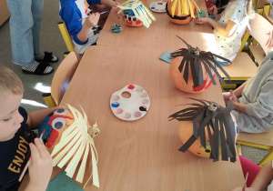 Dzieci tworzą postacie z dyni.