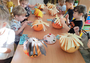 Dzieci tworzą postacie z dyni.
