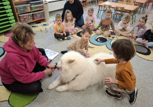 Dzieci czeszą psa.
