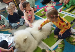 Dzieci czeszą psa.