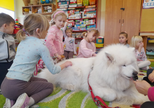 Dzieci czeszą psa.