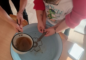 Dzieci czynią andrzejkowe wróżby.