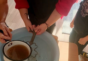 Dzieci czynią andrzejkowe wróżby.