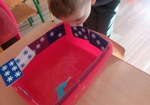 Dzieci czynią andrzejkowe wróżby.