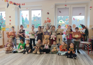 Dzieci bawią się z pluszowym misiem z okazji jego święta.