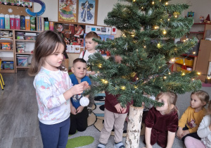 Dzieci ubierają choinkę.