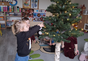 Dzieci ubierają choinkę.