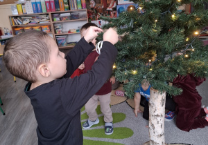 Dzieci ubierają choinkę.