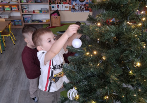 Dzieci ubierają choinkę.