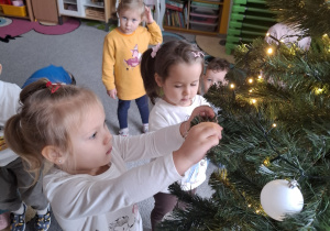 Dzieci ubierają choinkę.
