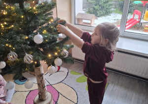 Dzieci ubierają choinkę.