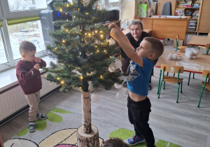 Dzieci ubierają choinkę.