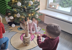 Dzieci ubierają choinkę.
