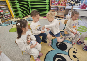 Dzieci przesypują śnieg sztuczny z kubeczka do kubeczka.