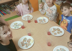 Dzieci jedzą pierniczki przy stoliku.